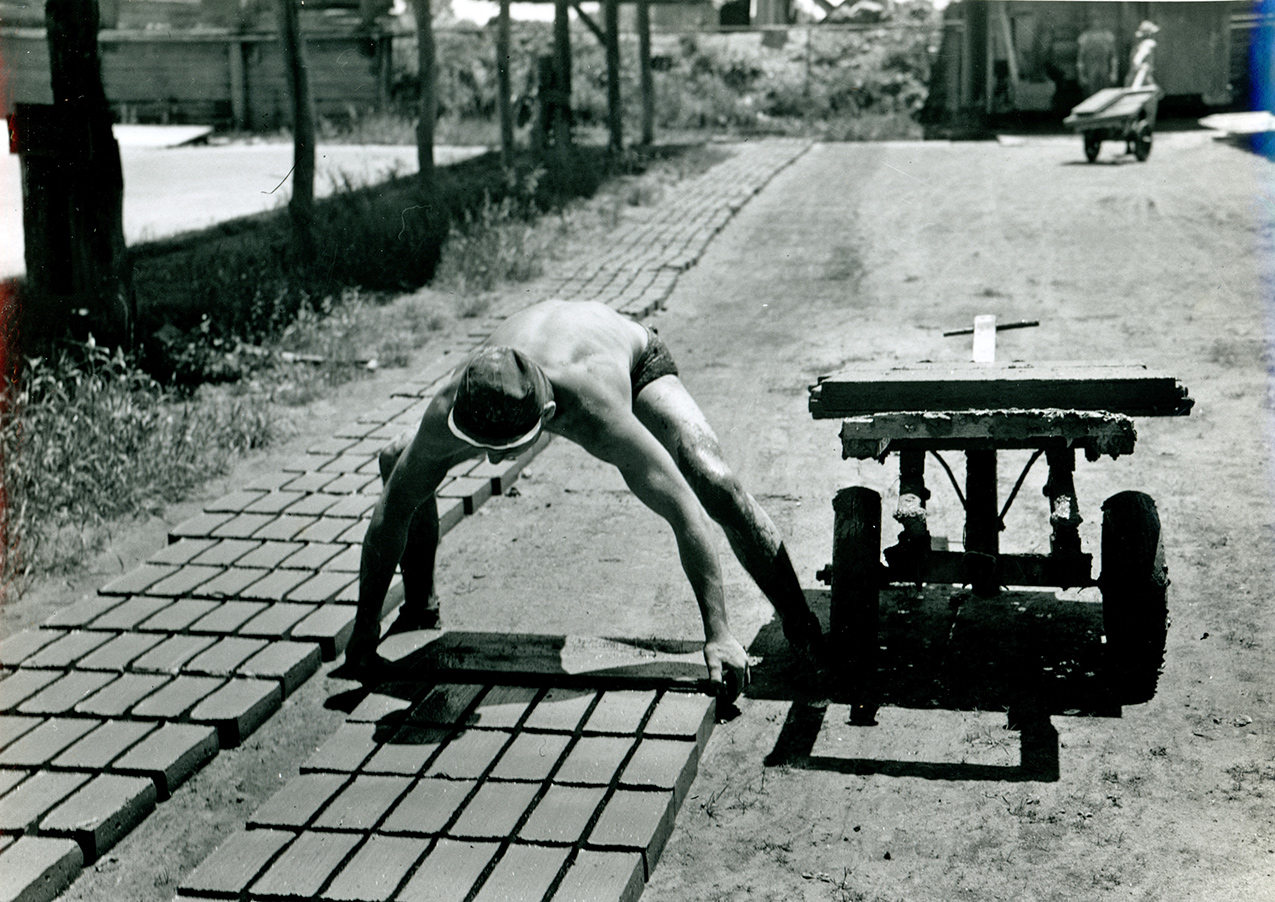 A man laying out bricks to dry at Mack Brickyard